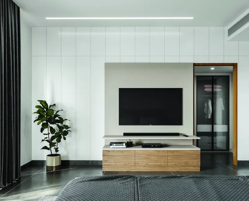 Bedroom TV wall with a white wardrobe and a wooden console in a 3 BHK home in Hosur, designed by Huma Interiors