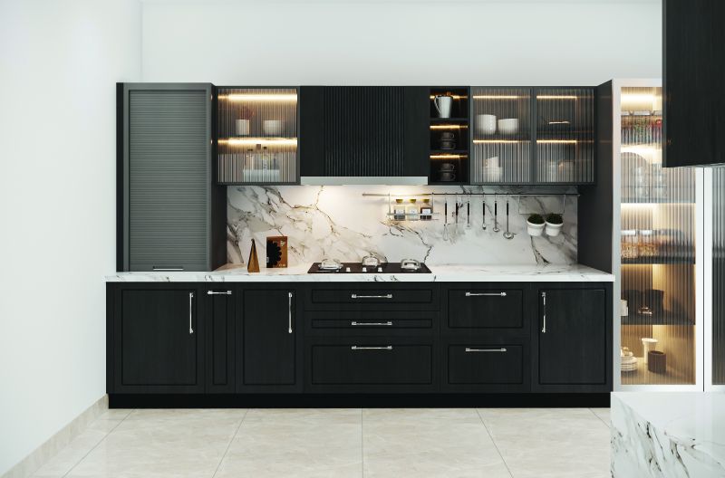 Straight kitchen wall with black base cabinets and lit glass shutters in a 2 BHK home in Bagaluru, designed by Huma Interiors